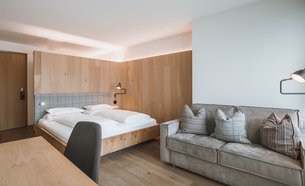 Modern hotel room with double bed, sofa, and desk