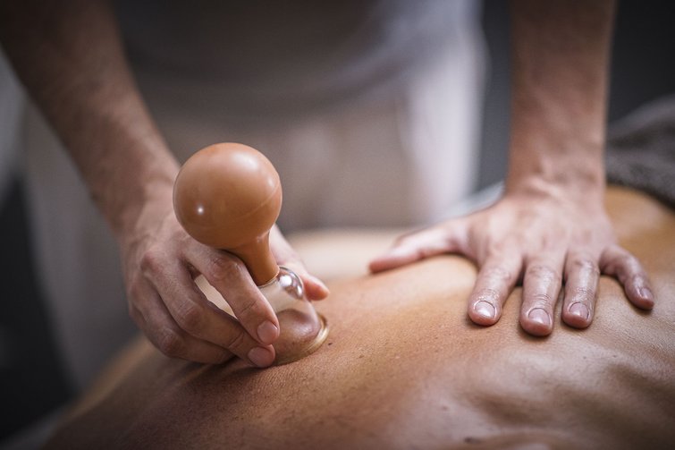 Massage mit Schröpfglas auf dem Rücken einer Person