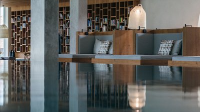 Area lettura moderna con scaffali in legno e sedute imbottite