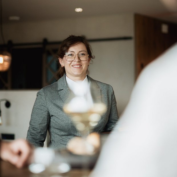 Frau in grauem Blazer lächelt bei einem Treffen in einem Café