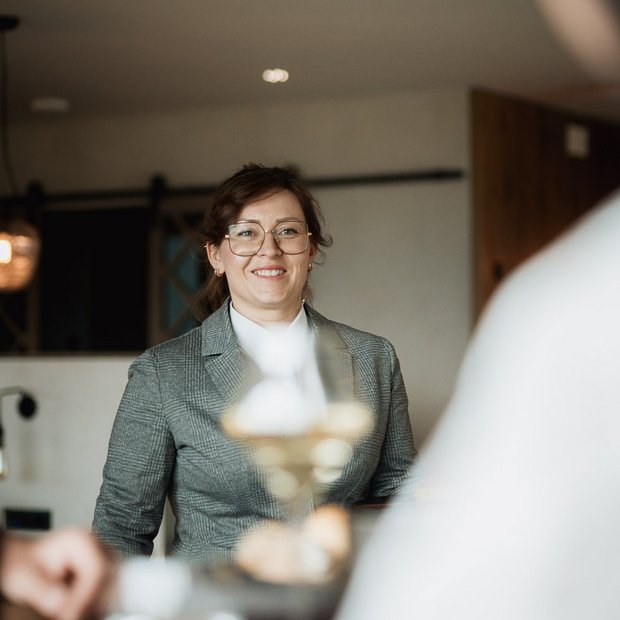 Woman in gray blazer smiling during a meeting at a café