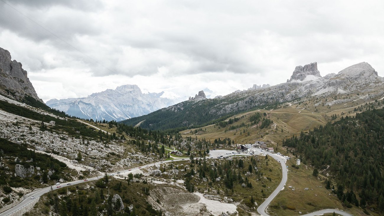 Bergstraße und Parkplätze in einem bewaldeten Tal mit wolkigem Himmel