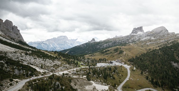Strada di montagna e parcheggi in una valle boscosa con cielo nuvoloso