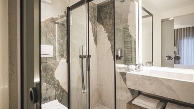 Bagno moderno con doccia in vetro e pareti in marmo