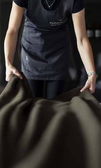 Person breitet Bettdecke in dunklem Raum aus