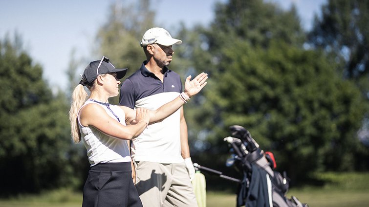 Due golfisti in campo da golf mentre parlano, sacca da golf sullo sfondo