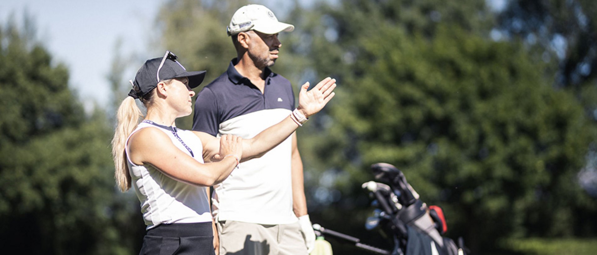 Zwei Golfer auf dem Golfplatz beim Gespräch, Golftasche im Hintergrund