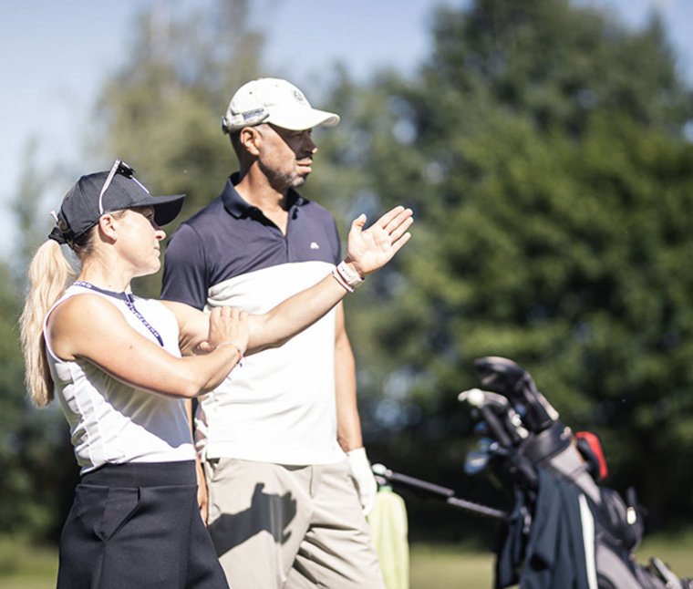 Zwei Golfer auf dem Golfplatz beim Gespräch, Golftasche im Hintergrund