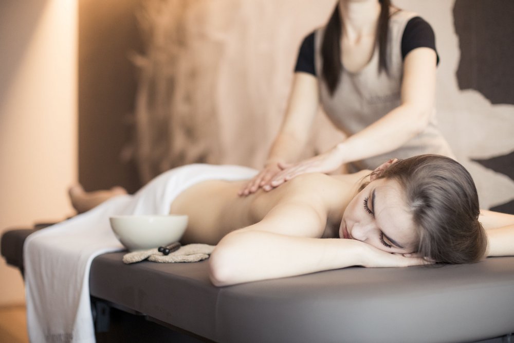 Frau erhält entspannende Rückenmassage auf Massagetisch