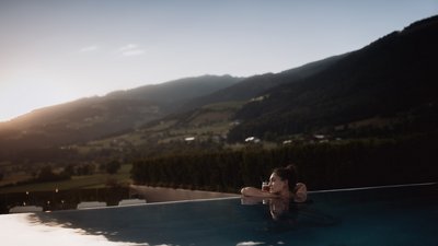 Photos from your hotel in Pfalzen in Val Pusteria/Pustertal Woman relaxing in infinity pool with mountain view at sunset