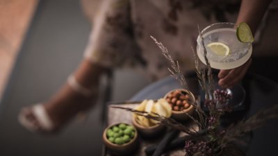 The best photos from our hotel in South Tyrol that kids love Hand holding cocktail with lime slices above snacks and flowers on table