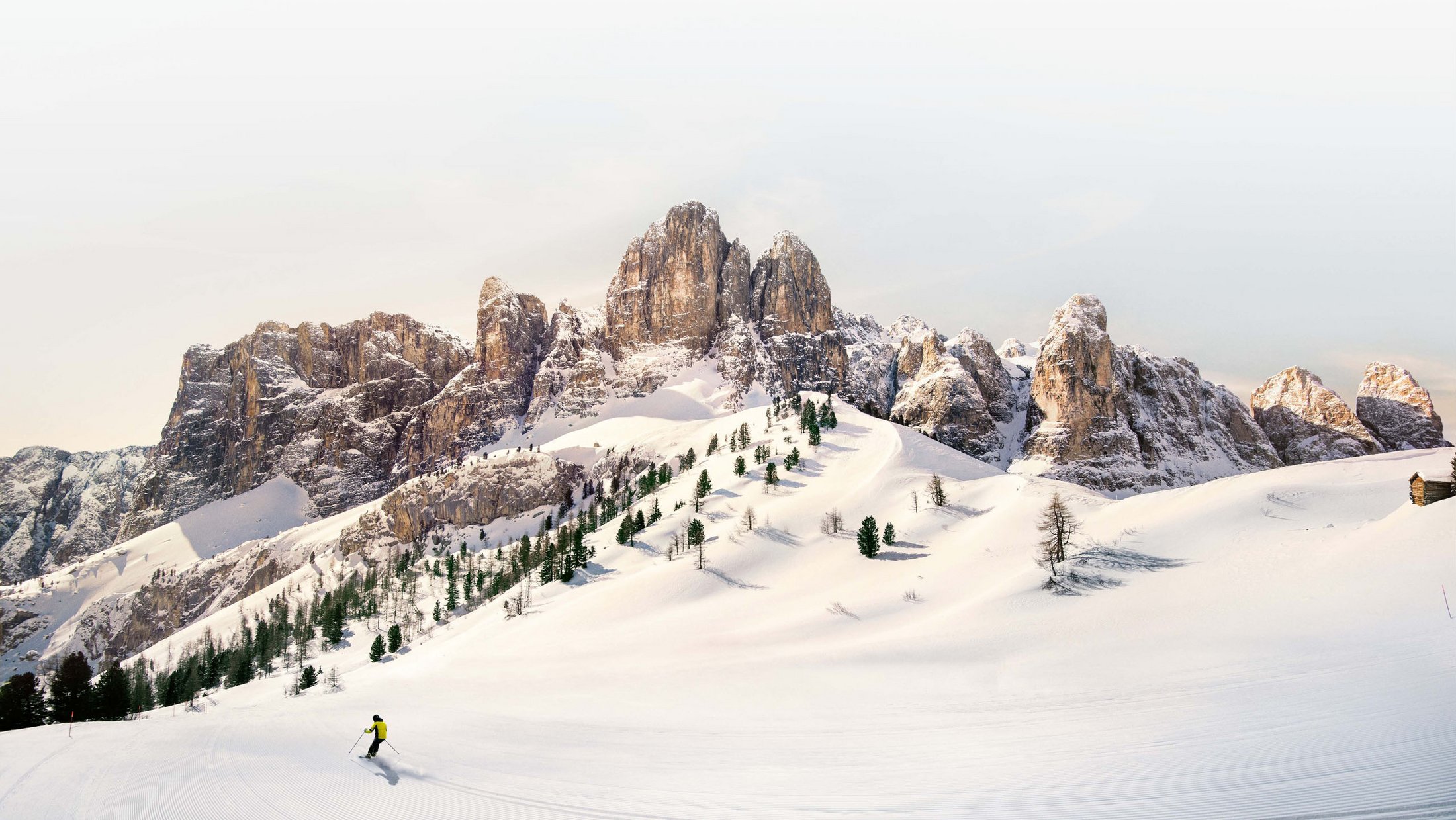 Skifahrer auf schneebedecktem Hang vor gebirgiger Landschaft