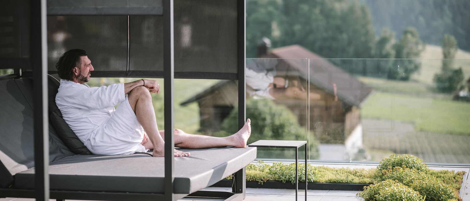Man in bathrobe relaxing on lounge chair with mountain view