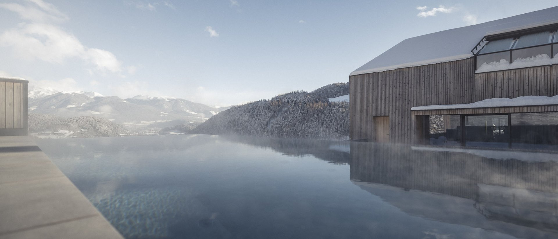 Infinity pool with mountain view and snowy wooden house under blue sky